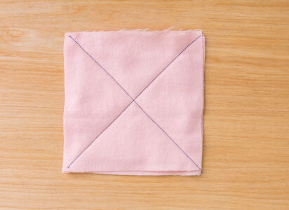 pink square of fabric with an X drawn connecting the corners